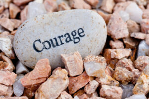 Courage written on a big smooth rock with jagged rocks